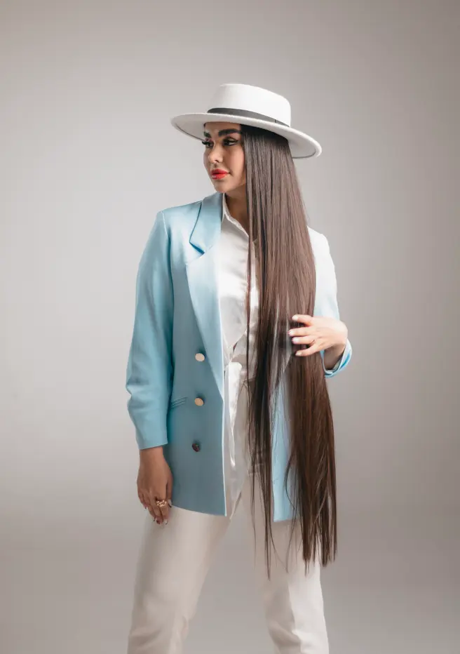 A model in a pale blue suit and white hat with long straight hair.