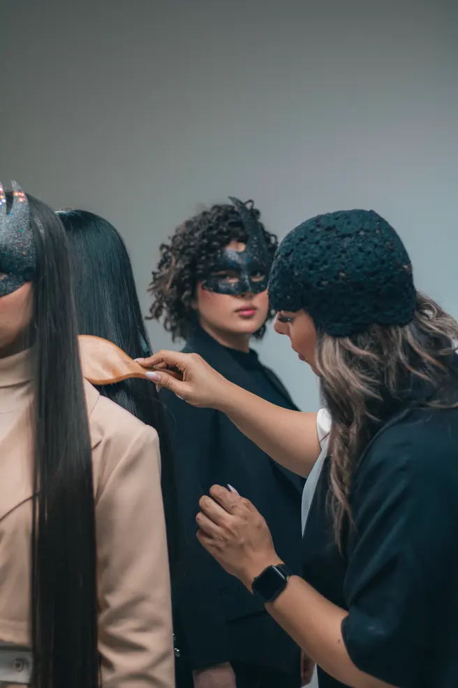 A hairstylist preparing models' hair backstage for an editorial shoot.